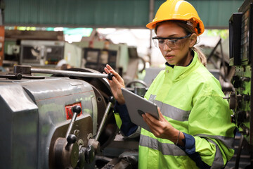 A Engineer woman using tablet or computer for inspect or checking or adjust or operate control the machine in workshop factory, the technician repair or maintenance part or equipment 