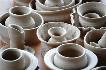 handmade unbacked crockery and pots on the table in the potter's studio. clay before firing in a ceramic kiln