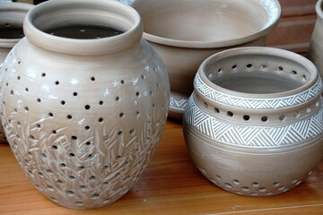 handmade unbacked crockery and pots on the table in the potter's studio. clay before firing in a...