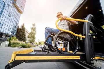 A man in a wheelchair on a lift of a vehicle for people with disabilities