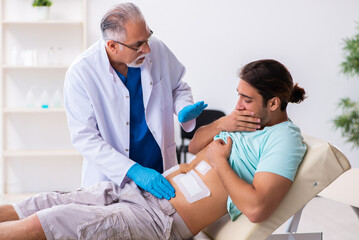 Fototapeta premium Injured young man visiting experienced male doctor