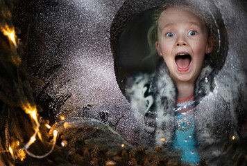 beautiful little girl surprised in frosted window