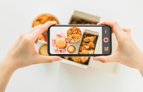 Hand using smartphone with fast food fried chicken photography.