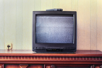 vintage tv screen with glitch static image stands on wooden table in room