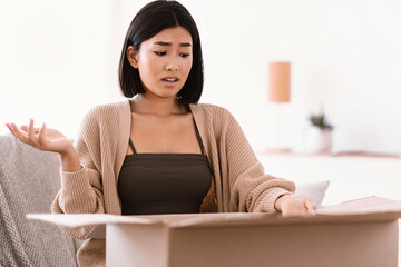Angry young woman unpacking wrong parcel, delivery mistake