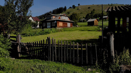 Fototapeta na wymiar Wooden huts with fence. Great houses on the green valley in the mountains.