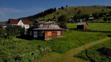 Fototapeta na wymiar Lovely houses in summer's mountains. Clear blue sky in green valley.