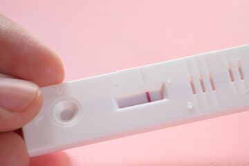 hand holding Pregnancy test kit on a wood desk.