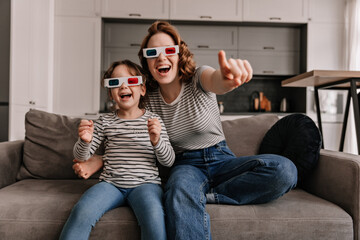 Naklejka premium Joyful mom and daughter are resting inapartment and watching movie in 3D with smile