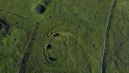 Quad bikes are making traces on the green grass. Topview of meadow with ATV on it.