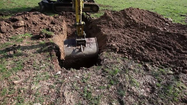 Mechanical shovel digging a hole in a meadow. Concept: industrial earthmoving activity