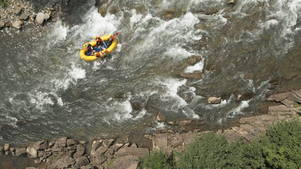 People in life vest are fighting with stream of river. Active teamwork for coming over dangerous rapids.