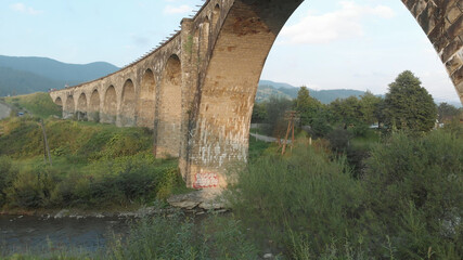 Old austrian bridge at the Karpatian mountains. Clear mountain river under bridge view from down.