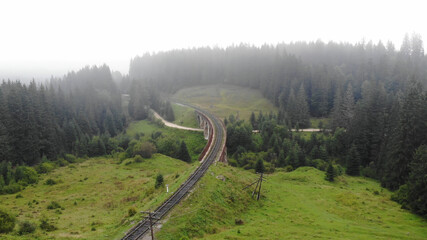 Aerial view of foggy landscape with railway bridge. Famous viaduct in Carpathians.