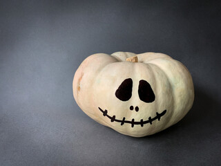 Halloween jack o lantern painted face white pumpkin on dark gray background with copy space