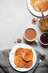 breakfast with a cup of coffee and small pancakes with honey and nuts