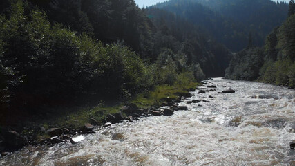 Fast flowing river. Dangerous rapids and big stones in the water. White seething water among the...