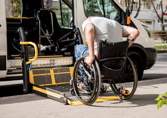Obraz premium A man in a wheelchair moves to the lift of a specialized vehicle 