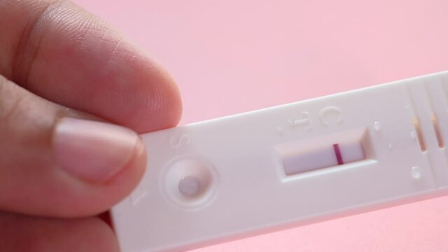 hand holding Pregnancy test kit on a wood desk.