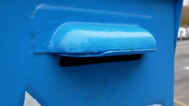 Woman hand is sending several letters into a blue mailbox