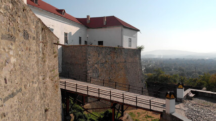 Ancient retractable bridge of the fortress. Strengthening the castle to protection against attack. Panorama of green town on the background.