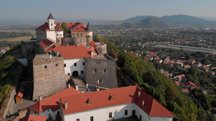 Beautiful scenery of medieval castle. Elegant facades with red roof tile. Mountains on the background.