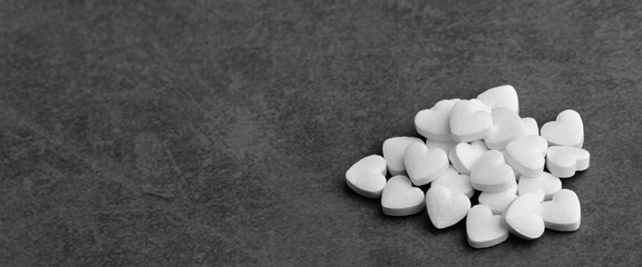 Fototapeta na wymiar White medical pills in the form of hearts on a gray background.