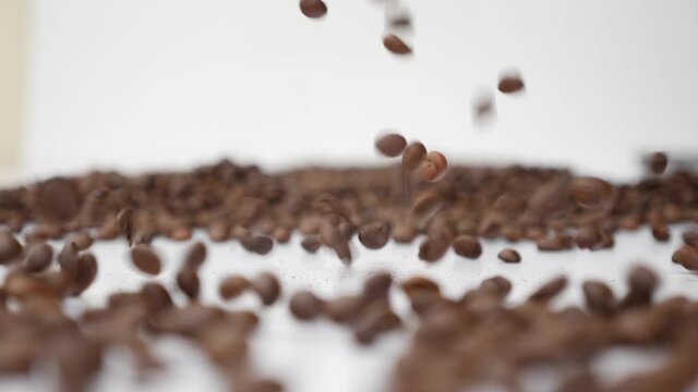 coffee beans falling slow motion white background close up
