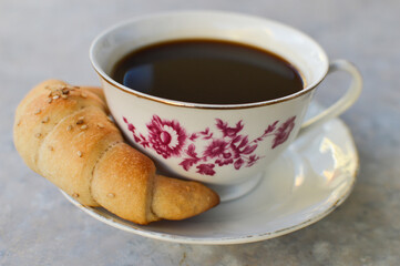 Vintage china cup of coffee with roll, side view