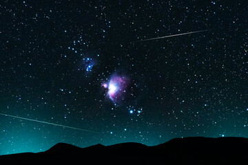 Fototapeta na wymiar Beautiful bright Orion galaxy over the hill and meteors on the starry sky. Deep space. Astronomy. 