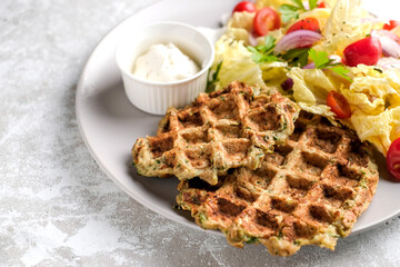 Vegetarian food of vegetable waffles with green salad, tomatoes on a plate