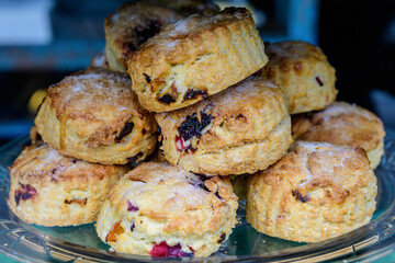 Freshly baked homemade English scones with dried fruits, displayed as a pyramid, available for sale at a café in London, side view of healthy food photographed with soft focus.