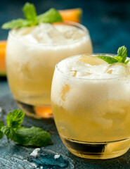 Refreshing Cantaloupe Melon cocktail with ice and mint on rustic table