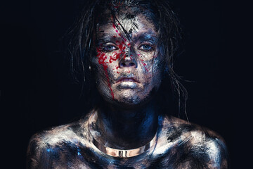 Fashion glamour portrait of a beautiful young caucasian woman on a black background. Creative makeup. Dramatic dark image. The effect of a dirty face with drops of blood, metal collar on the neck