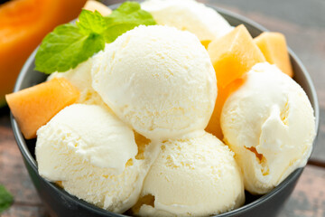 Melon ice cream with mint in bowl on wooden table