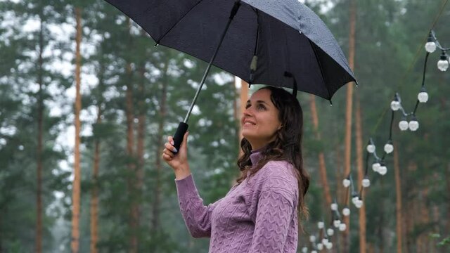 Smiling Woman with Umbrella Lending Hand for the Rain. Enjoying Rainfall in the Park. Autumn Season, Harmony with Nature and People concept