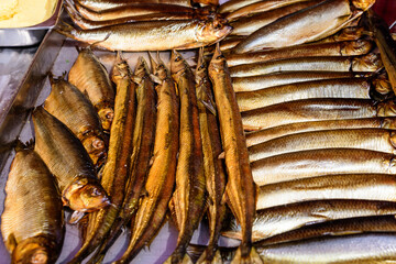 Different types of smoked fish prepared displayed for sale a street food festival, cooked and ready to eat healthy seafood, beautiful orange monochrome outdoor background.