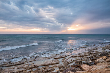 Fototapeta na wymiar Sunset on the background of the rocky seashore.