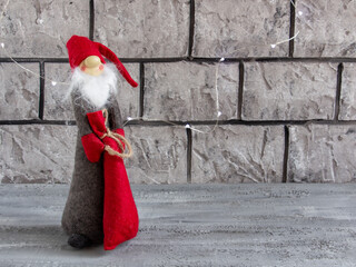 beautiful New Year composition - New Year's lights, Santa Claus or gnome with a bag of gifts on a concrete background
