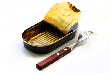 An open empty canned food from sardines with the leftover oil and a fork lie on a white background....