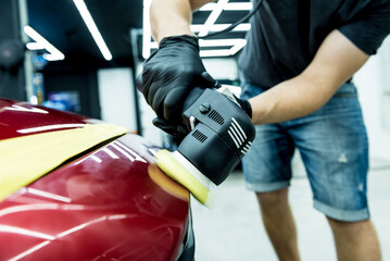 Fototapeta premium Car service worker polishes a car details with orbital polisher.