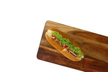 Hot dog with lettuce bacon and ketchup on wooden cutting board and isolated on white background. Sausage & bun