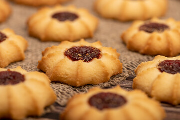 Homemade pastry cookies with jam on a background of homespun fabric with a rough texture, close-up, selective focus.