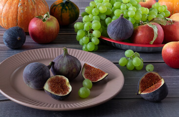 Ripe fresh figs, grapes, apples and pumpkins on a table with a wooden surface. Harvest, autumn fruits, healthy food. Horizontal orientation, selective focus.