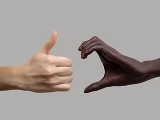 Black and white hand: one represents half a heart, the other a class icon on a gray isolated background. The concept of inter-racial friendship and respect, the fight against racism