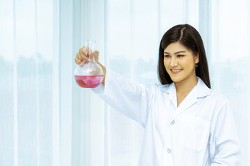 Portrait of beautiful scientist holding a round bottom bottle filled with purple solution.