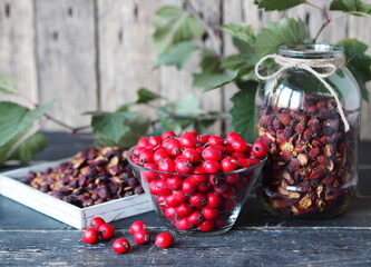 Useful properties of hawthorn berries. Harvesting of dried hawthorn for future use. Fresh red and dried hawthorn on a wooden background. Alternative traditional medicine using hawthorn.