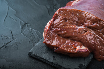 Raw beef liver on black background with copy space
