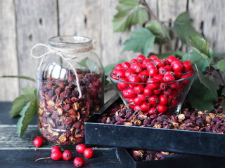 Useful properties of hawthorn berries. Harvesting of dried hawthorn for future use. Fresh red and dried hawthorn on a wooden background. Alternative traditional medicine using hawthorn.