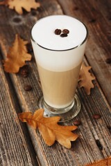 Coffee latte with beans and oak leaves on the table